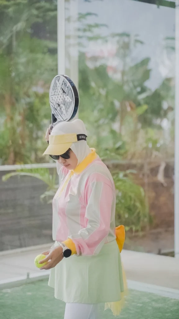wanita memegang bola dan raket padel bersiap service