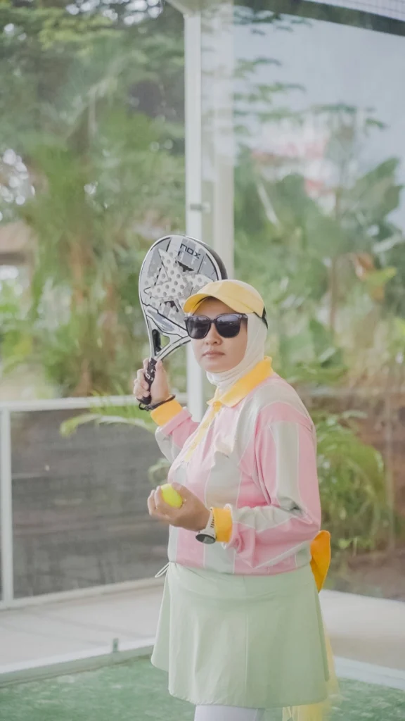 wanita memegang bola dan raket padel bersiap service