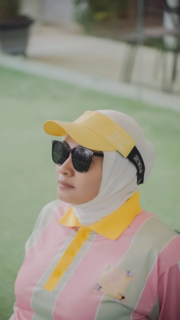 wanita duduk sebelum main padel dengan kacamata dan topi dan kerudung