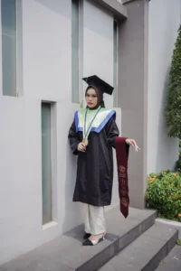 Aila Stikes Purwokerto Aston dalam foto wisuda mereka berdiri dalam pakaian sarjana, menunjukkan momen akademik penting mereka.