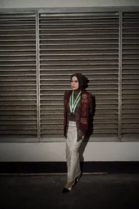 Aila Stikes Purwokerto Aston dalam momen penghargaan wisuda, berdiri di atas medali dengan latar belakang grating metali.