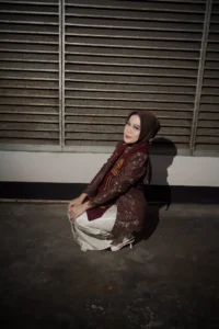 Aila Stikes Purwokerto Aston sedang mengikuti acara wisuda di atas tanah dengan tampilan maroon dan putih.