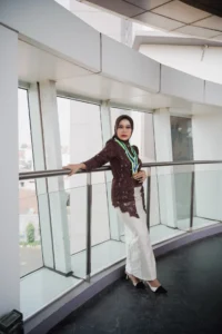 Aila Stikes Purwokerto Aston sedang mengambil foto wisuda sambil berdiri di sisi railing.