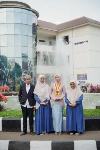 Wisuda Kristina UMP di Universitas Muhammadiyah Purwokerto, sebuah grup orang berdiri di depan sebuah fountain.