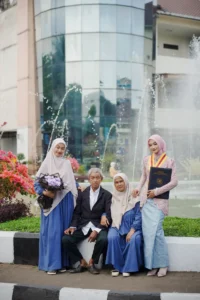 Wisuda Kristina UMP di Universitas Muhammadiyah Purwokerto, diikuti oleh sekelompok orang yang berpose di depan sebuah fountain.