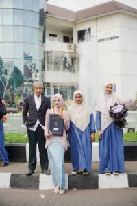 Wisuda Kristina UMP di Universitas Muhammadiyah Purwokerto, di depan sebuah fountain.