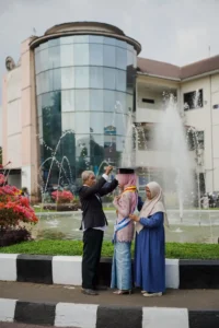 Kristina UMP mengambil foto dengan teman di depan fountains di Universitas Muhammadiyah Purwokerto.