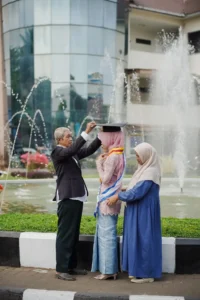 Krismina, seorang mahasiswa Universitas Muhammadiyah Purwokerto, sedang berfoto dengan teman-temannya di depan fountains, sementara dia menyesuaikan headscarf teman perempuannya.