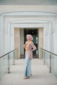 Seorang wanita dalam pakaian berwarna merah dan putih berdiri di antara pintu-pintu di Universitas Muhammadiyah Purwokerto.