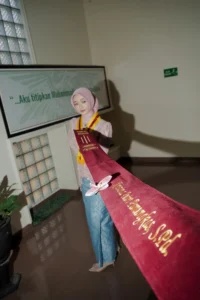 Seorang wanita berpakaian merah sedang memegang sebuah ribbons berwarna merah di Universitas Muhammadiyah Purwokerto.