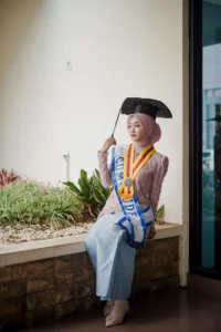 Kristina dari Universitas Muhammadiyah Purwokerto dalam acara wisuda sedang memegang parasu.