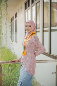 Kristina, seorang mahasiswa Universitas Muhammadiyah Purwokerto, memamerkan dirinya dalam foto wisuda berpakaian pakaian feminin di depan gedung universitas.