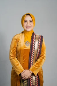 Seorang wanita memakai pakaian berwarna kuning dan emas sedang berpose untuk foto di Purbalingga.