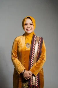 Seorang wanita dalam pakaian tradisional, tersenyum dan berpose untuk kamera, foto ini merupakan profil kepala Kementerian Kebudayaan dan Pariwisata Provinsi Purbalingga.