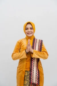 Seorang wanita dalam pakaian hijau berdiri dengan tangan bersamaan di depannya, foto ini merupakan profil kepala Kementerian Kebudayaan dan Pariwisata Provinsi Purbalingga.