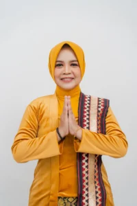 Seorang wanita dalam pakaian kuning, tangan di depan dada, tersenyum dan berpose, foto ini merupakan profil kepala Kementerian Kebudayaan dan Pariwisata Provinsi Purbalingga.