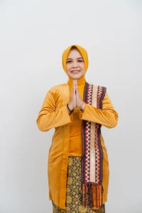Seorang wanita berpakaian hijau berdiri dengan tangan bersama di depannya.