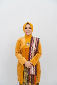 Seorang wanita dalam pakaian hijau berdiri dengan tangan bersamaan, foto ini merupakan profil kepala Kementerian Kehagian Provinsi Purbalingga.