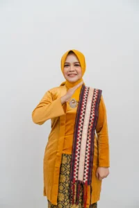 Seorang wanita berpakaian kuning dan orange sedang mengambil foto sementara menyingkirkan sepatu.