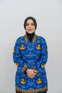 Seorang pejabat kepala kementerian berdiri dengan tangan bersamaan, memakai pakaian pola biru dan hitam.